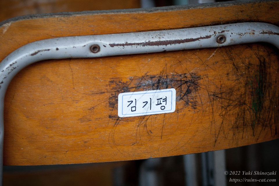 ハングルで氏名が書かれたシールの貼られた教室の椅子